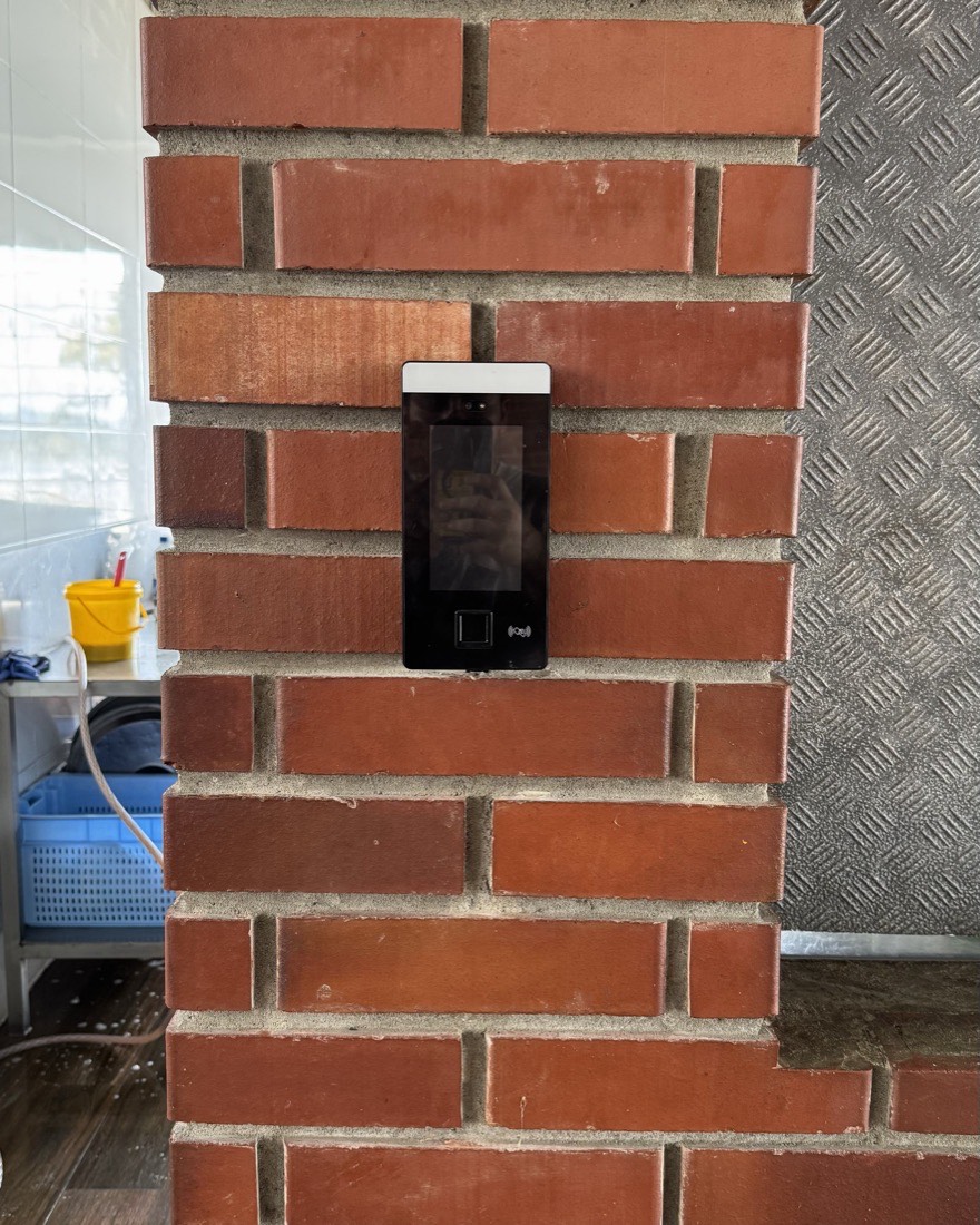 Terminal de reconocimiento facial montado en columna de la planta para marcar asistencia